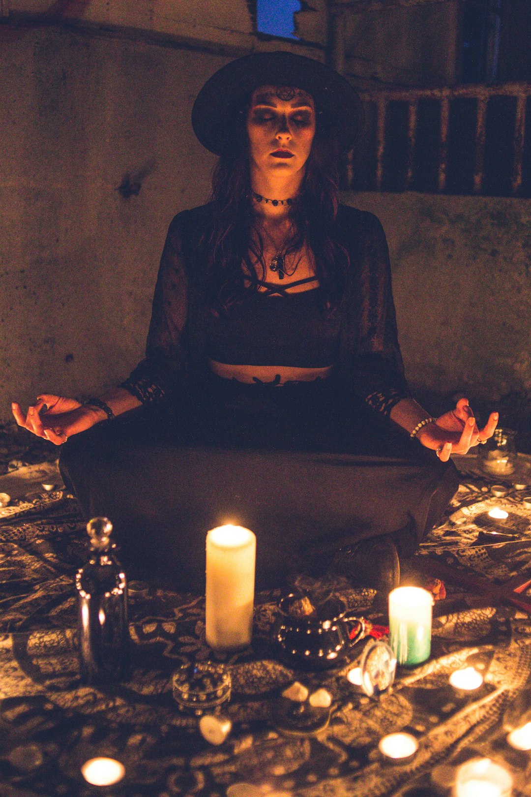 woman-in-black-long-sleeve-shirt-sitting-on-chair-in-front-of-candles-zygpjwizzau